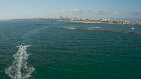 Speedboat-cruising-on-Atlantic-coastline-towards-Portimao,-Aerial-following