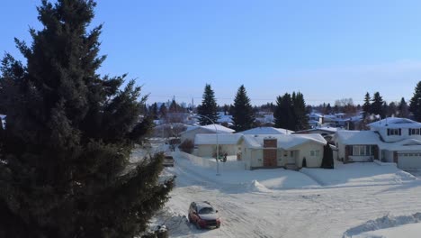 aerial-reveal-panout-of-snow-covered-winter-town-of-low-rise-quant-cozy-white-bed-in-breakfast-dettached-homes-brick-rectangular-chimney-and-snowed-in-roads-cars-paths-with-tall-fraser-fir-trees-2-2