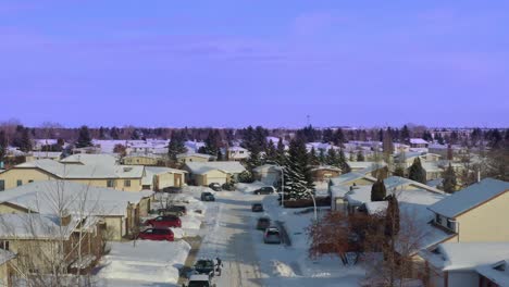 Arial-Panout-über-Blauem-Himmel-Schneebedeckte-Autos-Lieferwagen-Straßen-Bürgersteige-In-Einer-Seitenstraße-Eines-Edmonton-Alberta-Subarb-Der-Mittleren-Bis-Oberen-Klasse-Nahaufnahme-Von-Niedrig-Angehobenen-Freistehenden-Häusern,-Die-Die-Hypothek-Abbezahlt-Haben