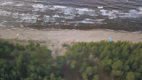 Aerial-shot-of-a-group-of-paraglider-trying-to-take-off-on-a-beach-in-Latvia