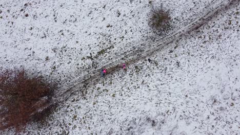 Drone-orbit-shot-people-walking-in-snowy-field-countryside-UK-3