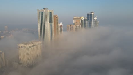 Nebel-In-Den-Vereinigten-Arabischen-Emiraten:-Blick-Von-Oben-Auf-Dichten-Nebel-über-Dem-Al-Majaz-Gebiet-Von-Sharjah,-Skyline-Von-Sharjah-Im-Wintermorgennebel,-Vereinigte-Arabische-Emirate,-4K-Drohnenaufnahmen