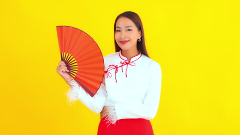 Una-Mujer-Asiática-Bastante-Joven-Sostiene-Un-Ventilador-Rojo