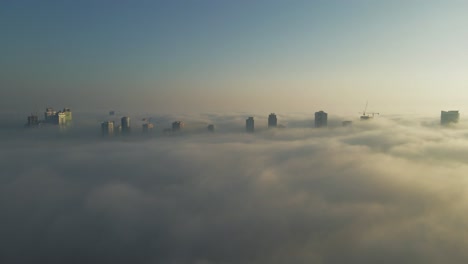 Drone-view-of-Fog-over-Sharjah,-Sharjah-skyline-covered-in-the-winter-morning-fog,-United-Arab-Emirates,-4K-Drone-Footage