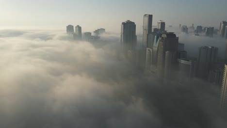 FOG-IN-UAE:-Aerial-view-of-Fog-over-Sharjah's-Khalid-Lake,-Sharjah-skyline-covered-in-the-winter-morning-fog,-United-Arab-Emirates,-4K-Drone-Footage