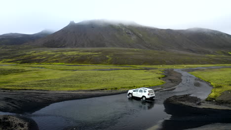 Drohnen-Luftaufnahmen-Eines-Weißen-4x4-Autos,-Das-Durch-Einen-Fluss-Fährt,-Der-Das-Hochland-Von-Island-Durchquert