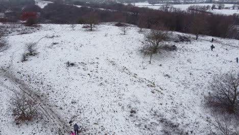 Drone-rising-shot-people-walking-in-snowy-field-countryside-UK-2