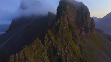 Drone-aerial-footage-of-Coastal-mountains-and-cliffs-near-Stokkness-at-sunrise-with-beautiful-layer-of-clouds-in-Iceland