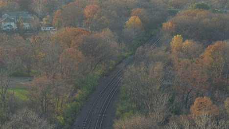 Antenne-Von-Bahngleisen,-Die-An-Einem-Schönen-Herbsttag-Im-November-Durch-Herbstbäume-In-Der-Nähe-Von-Häusern-In-Der-Nachbarschaft-Von-Kirkwood-Schneiden