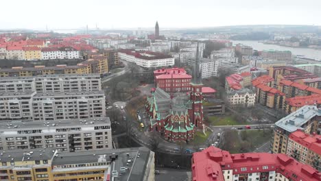 Stunning-zoom-out-aerial-view-of-downtown-Oscar-Fredrik-Church-surrounded-by-skyline-and-buildings-on-a-cloudy-and-rainy-winter-day-in-Gothenburg-City,-Sweden
