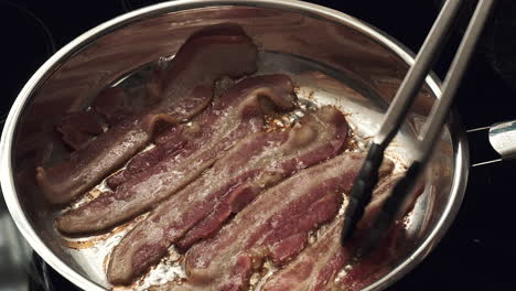Bacon-frying-in-pan-tended-being-tended-by-a-chef
