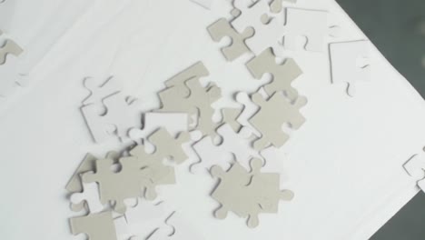 White-and-gray-puzzle-pieces-falling-on-a-white-surface-and-bouncing-and-spinning-back-with-a-dark-background
