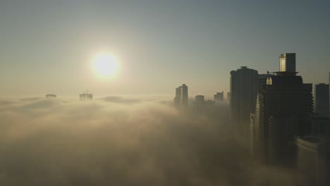 Aerial-view-of-Fog-over-Sharjah,-Sharjah-skyline-covered-in-the-winter-morning-fog,-United-Arab-Emirates,-4K-Drone-Footage