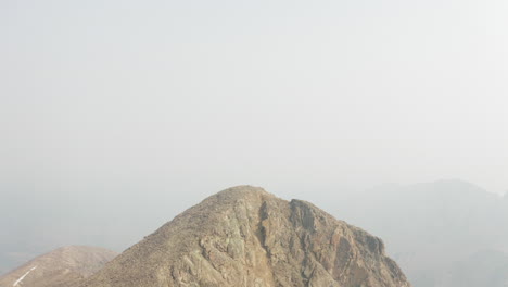 Vista-Ascendente-Del-Excursionista-En-La-Cima-De-La-Montaña-Rocosa---Antena-4k