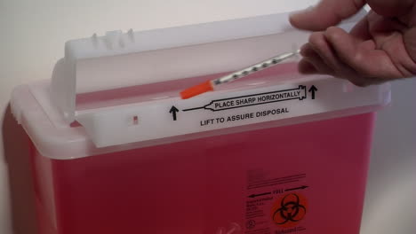 Disposing-of-a-used-syringe-in-a-sharps-container