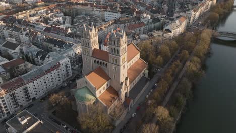 Aerial-Birdseye-5k-Drohne-über-Dem-Dach-Der-St.-Maximilian-Kirche-Und-Der-Isar-Mit-Münchner-Stadtbild,-Deutschland
