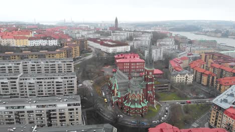 Stunning-aerial-flying-towards-Oscar-Fredrik-Church-surrounded-by-skyline-and-buildings-on-a-cloudy-winter-day-in-Gothenburg-City,-Sweden