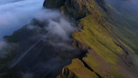 Drone-aerial-footage-of-Coastal-mountains-and-cliffs-near-Stokkness-at-sunrise-with-clouds-in-Iceland