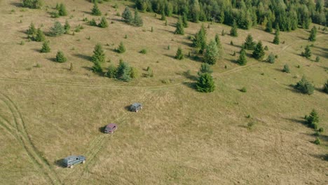 Vehicles-Traveling-On-Meadow-Green-Hills-With-Dense-Pine-Trees-During-Daytime-In-Radocelo,-Central-Serbia