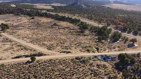 Vista-Aérea,-Drone-Volando-Sobre-La-Carretera-Rural-En-Norwood,-Colorado-Rodeado-De-Arbustos-Verdes