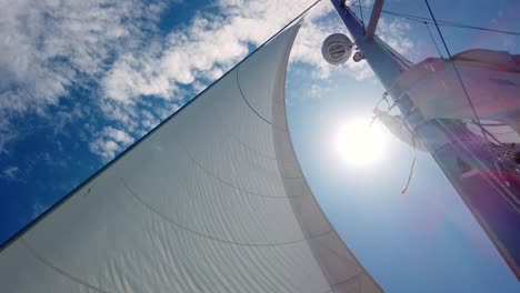 Slow-motion-shot-of-giant-white-sail-while-sailing-in-windy-and-sunny-summer-day