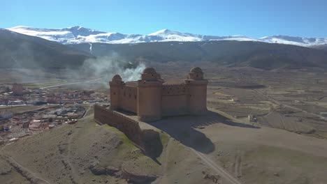Luftaufnahme-Der-Burg-Von-La-Calahorra-Mit-Sierra-Nevada-Dahinter-In-Granada,-Spanien