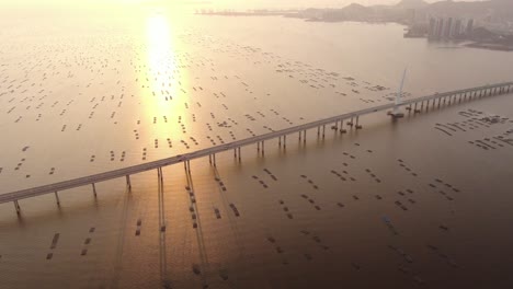 Verkehr-Auf-Der-Hong-Kong-shenzhen-Bay-Bridge-Bei-Sonnenuntergang,-Mit-Fisch--Und-Austernzuchtpools,-Luftbild