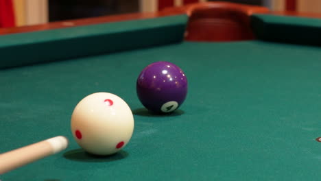 Closeup-of-Person-Playing-Pool-Shooting-Solid-Purple-4-Ball-into-Corner-Pocket-after-Practice-Strokes-using-Cue-Ball-with-Red-Spots,-Open-Bridge-Hand-with-Wooden-Cue-Stick-and-Green-Felt-or-Cloth