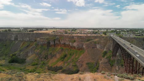 Slow-downward-aerial-tilt-towards-the-Snake-River-Canyon-with-the-Perrine-Memorial-Bridge-in-Twin-Falls,-Idaho-during-the-summer