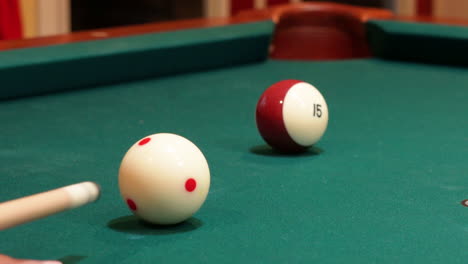 Closeup-of-Person-Playing-Pool-Shooting-Striped-Brown-15-Ball-into-Corner-Pocket-after-Practice-Strokes-using-Cue-Ball-with-Red-Spots,-Open-Bridge-Hand-with-Wooden-Cue-Stick-and-Green-Felt-or-Cloth