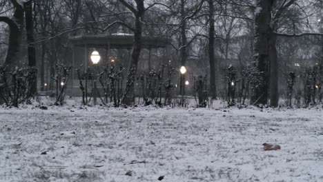 Low-tracking-shot-of-the-kiosk-in-the-snowy-Brussels-park-enlightened-with-warm-colored-lamps