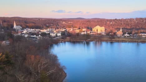 Aerial-drone-footage-riding-up-from-behind-pine-trees-and-over-a-small-lake-town-during-winter-in-America
