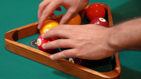 Person-Racks-9-Ball-Pool-Diamond-Closeup-on-the-Spot-and-Arranges-Solid-and-Striped-Billiard-Balls-on-Table-with-Green-Felt-or-Cloth-and-Tightening-Rack-with-Hands-before-Lifting-Wooden-Triangle