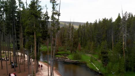 Slow-downward-aerial-tilt-above-a-large-river-and-picnic-area-among-the-trees-near-Yellowstone-in-Wyoming