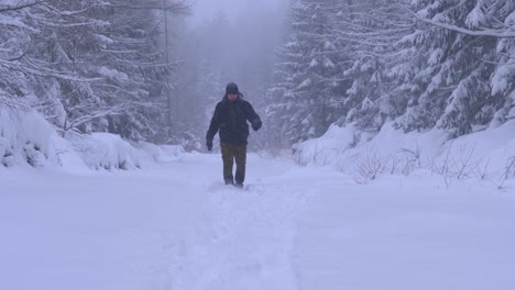 Man-walking-in-the-forest-through-heavy-snow-on-a-beautiful-winter-day