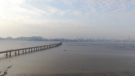 Puente-De-La-Bahía-De-Hong-Kong-Shenzhen-Con-Edificios-Tin-Shui-Wai-En-El-Horizonte-Y-Piscinas-De-Cultivo-De-Peces-Y-Ostras,-Vista-Aérea