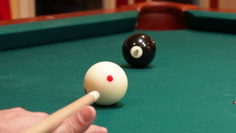 Closeup-of-Person-Playing-Pool-Shooting-Solid-Black-8-Ball-into-Corner-Pocket-after-Practice-Strokes-using-Cue-Ball-with-Red-Spots,-Open-Bridge-Hand-with-Wooden-Cue-Stick-and-Green-Felt-or-Cloth