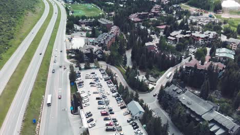 Slow-descending-aerial-shot-over-a-main-road-next-to-Vail-Ski-Resort-in-Colorado-during-the-summer