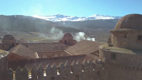 Aerial-descending-shot-over-the-Castle-of-La-Calahorra-with-Sierra-Nevada-behind-on-sunny-winter-day