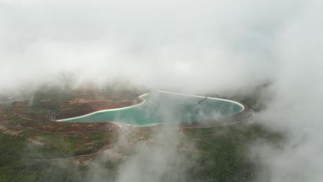 Magical-mist-around-blue-fresh-water-reservoir-in-mountains,-aerial