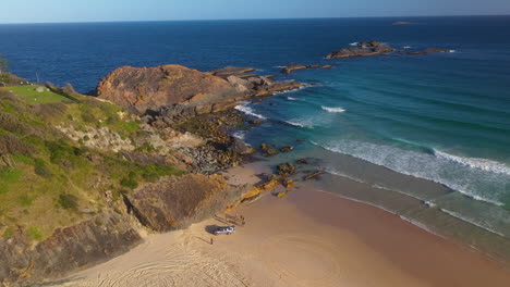 Australian-beachgoers-on-secluded-beach-at-sunset,-aerial-view