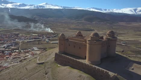 Luftaufnahme-Rund-Um-Die-Festung-La-Calahorra-In-Granada-Mit-Schneebedeckter-Sierra-Nevada-Dahinter