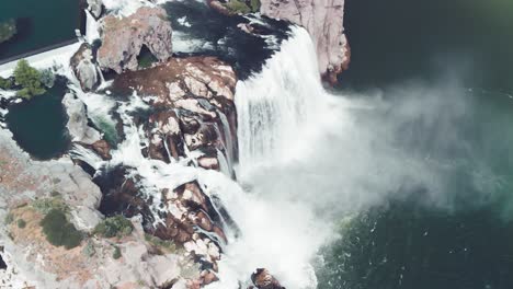 Slow-motion-upward-aerial-tilt-of-Shoshone-Falls-expelling-a-cloud-of-mist-into-the-Snake-River-in-Twin-Falls,-Idaho