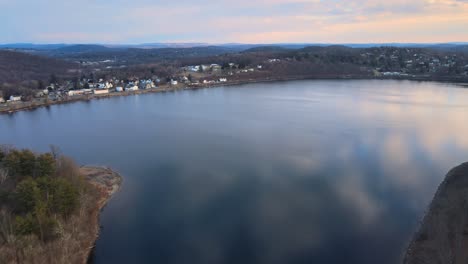 Aerial-drone-footage-over-a-pristine-lake-approaching-a-small-lakefront-town-in-America-during-winter
