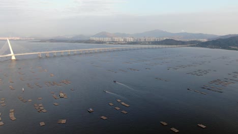 Hong-Kong-Shenzhen-Bay-Bridge-Mit-Tin-Shui-Wai-Gebäuden-Am-Horizont-Und-Fisch--Und-Austernzuchtbecken,-Luftbild