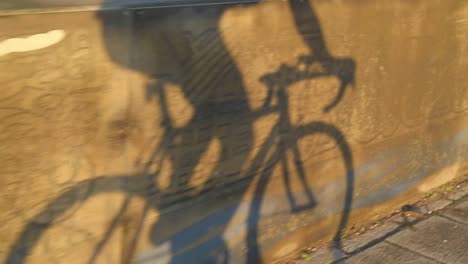 Zeitlupe-Tilt-Shot-Schatten-Des-Radfahrers,-Der-Fahrrad-Fährt,-Um-Bei-Sonnenaufgang-Und-Sonnenuntergang-Zur-Arbeit-Zu-Pendeln