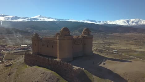 Aerial-view-of-the-castle-of-La-Calahorra-with-Sierra-Nevada-behind-in-Granada,-Spain