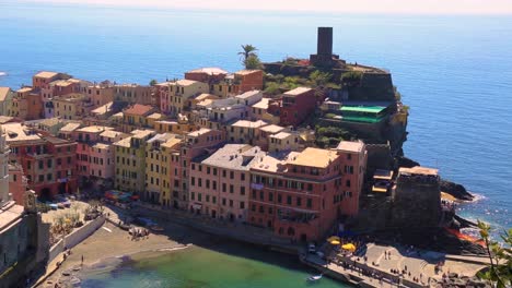 Static-view-overlooking-Vernazza-harbor-and-bay-with-colorful-houses-and-blue-ocean-on-a-sunny-summer-day-in-Vernazza,-Cinque-Terre,-Liguria-Italy