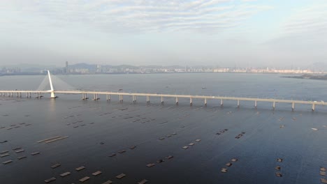 Puente-De-La-Bahía-De-Hong-Kong-Shenzhen-Con-Edificios-Tin-Shui-Wai-En-El-Horizonte-Y-Piscinas-De-Cultivo-De-Peces-Y-Ostras,-Vista-Aérea