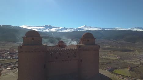 Drohne-Nahaufnahme-Des-Schlosses-Von-La-Calahorra-Mit-Der-Sierra-Nevada-Dahinter-Im-Winter